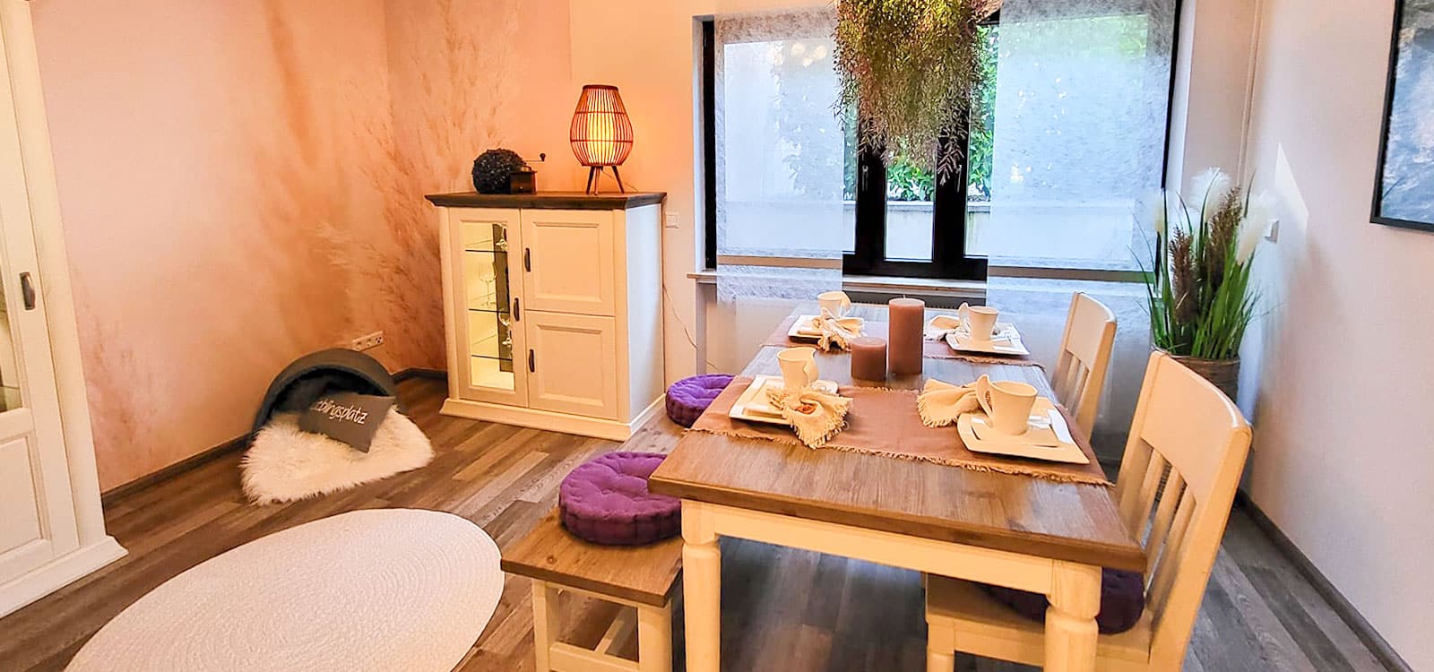 Ein Esszimmer mit einem Holztisch, zwei Stühlen und einem kleinen Sideboard.